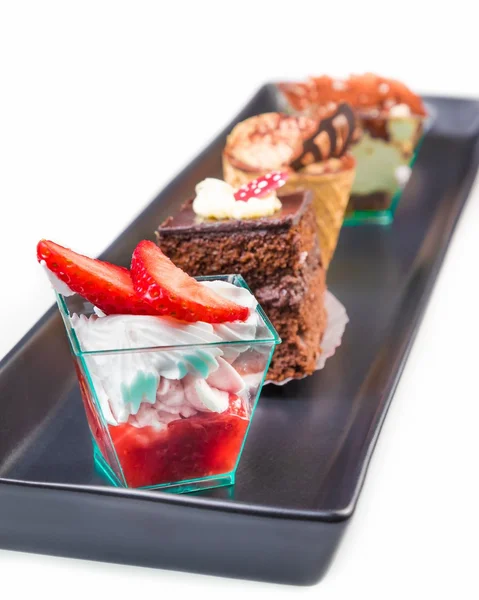 Délicieux gâteau aux fraises avec crème devant des petits gâteaux au chocolat et au café — Photo