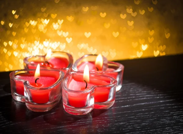 Candele rosse a forma di cuore ardente su cuori dorati bokeh Foto Stock Royalty Free