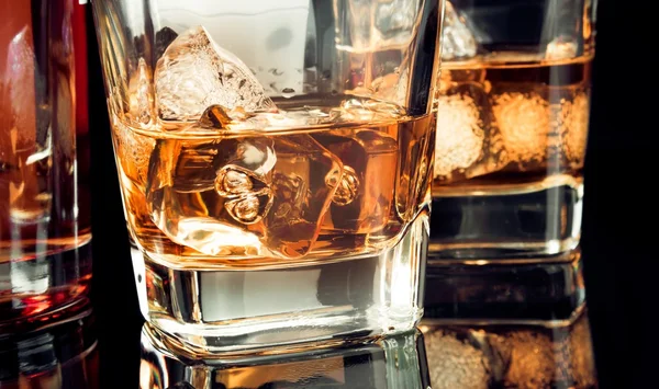 Whisky z lodem w szkło na czarnym tle w pobliżu butelka — Zdjęcie stockowe