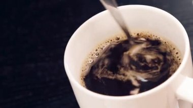 Üst kısmındaki fincan kahve bir kaşık içinde siyah ahşap tablo kullanmak yetişkin el ile görünümü