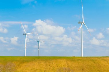 Rüzgar enerjisi türbinleri bir beyaz bulutlar ile mavi gökyüzünün altında en temiz, yenilenebilir elektrik enerji kaynağının vardır