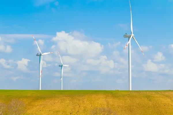 Le turbine eoliche sono una delle più pulite, fonte di energia elettrica rinnovabile, sotto il cielo blu con nuvole bianche Foto Stock Royalty Free