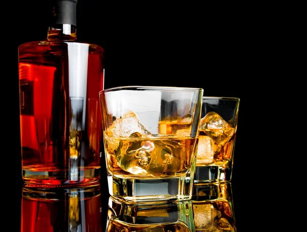 Två whisky med is i glasen nära flaskan på svart bakgrund — Stockfoto