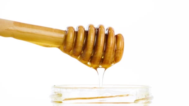 Otevřené med sklenice s detail dřevěné honey naběračka na vrcholu s kapku medu — Stock video