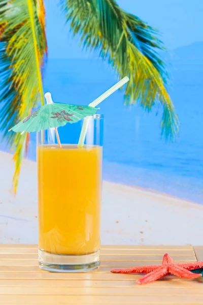 ヒトデの近くの砂浜のビーチでオレンジ ジュースのガラス — ストック写真