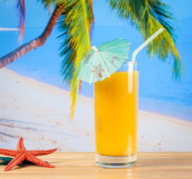 Deniz yıldızı yakınındaki kum plajındaki portakal suyu bir bardak