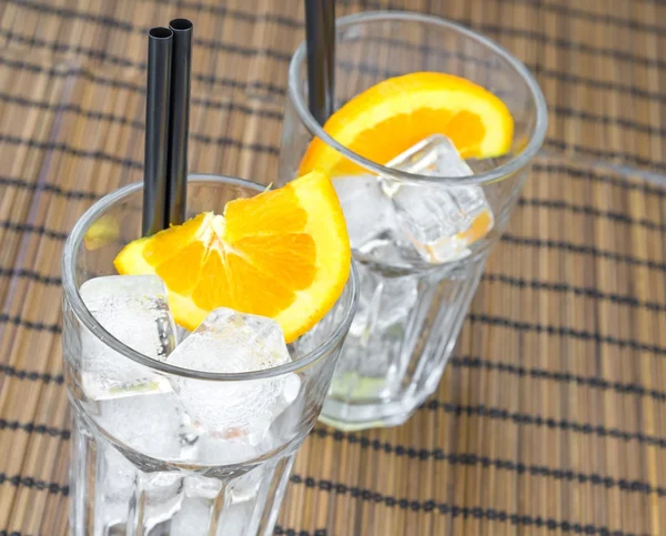 Topo de vista de copos de cocktail vazios com duas fatias de laranja e cubos de gelo — Fotografia de Stock