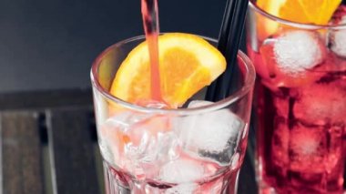 Barman ahşap masada iki portakal dilimleri ve buz küpleri ile kırmızı spritz aperitif aperol kokteyl dökme