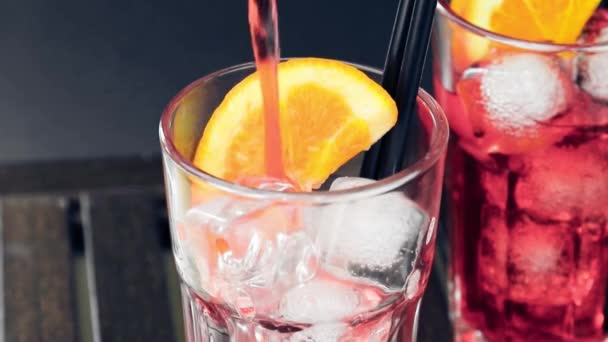 Barman nalewanie czerwonego Spritz aperitif Aperol koktajl z dwóch plasterków pomarańczy i kostki lodu na drewnianym stole — Wideo stockowe