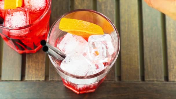 Blick von oben auf das Einschenken von Aperitif-Cocktail mit rotem Spritz mit Orangenscheiben und Eiswürfeln — Stockvideo