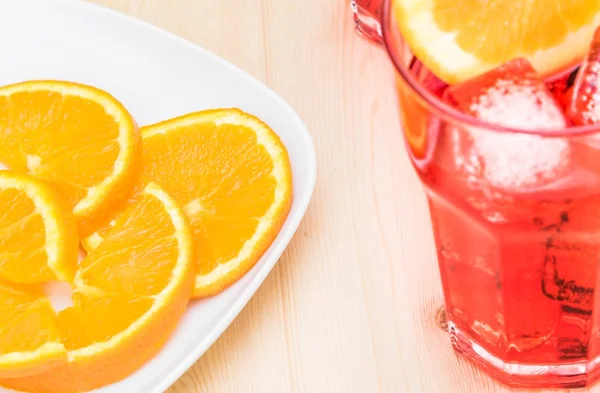 Plate of slices oranges near glass of spritz aperitif aperol cocktail with orange slices — Stock Photo, Image