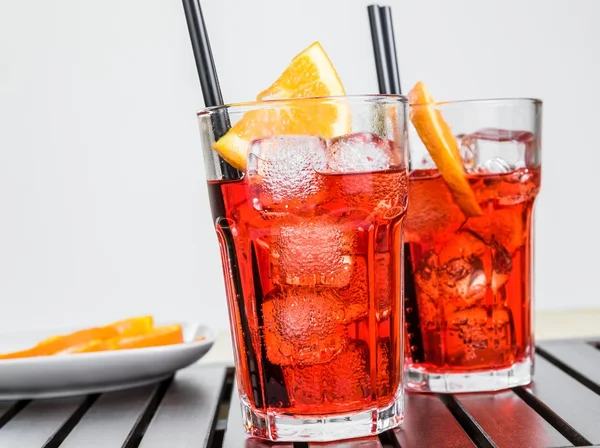 Glasses of spritz aperitif aperol cocktail with orange slices and ice cubes near plate of slices oranges — Stock Photo, Image