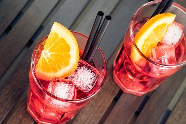 Primo piano di vista di occhiali di aperitivo di spritz cocktail rosso di aperol con fette arancioni e cubetti di ghiaccio — Foto Stock