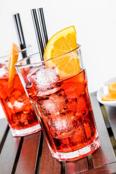 Copos de aperitivo aperol coquetel spritz com fatias de laranja e cubos de gelo perto da placa de laranjas de partes — Fotografia de Stock