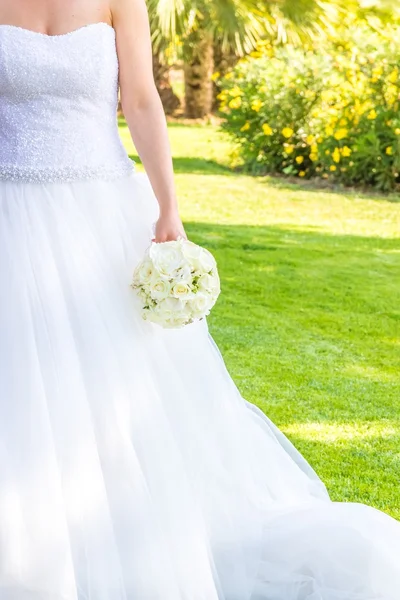 Novia tiene en la mano un ramo de flores de boda en un jardín — Foto de Stock