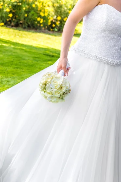 Braut hält Hochzeitsstrauß im Garten in der Hand — Stockfoto