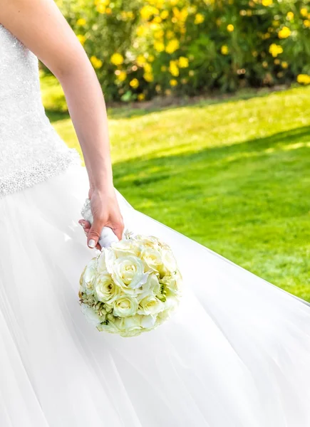 Braut hält Hochzeitsstrauß im Garten in der Hand — Stockfoto
