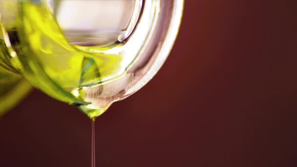 Hälla olivolja med makro sjunker med flaska på brun trä bakgrund — Stockvideo