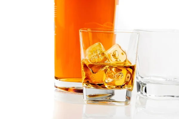 Two glasses of whiskey near bottle on white background with reflection — Stock Photo, Image