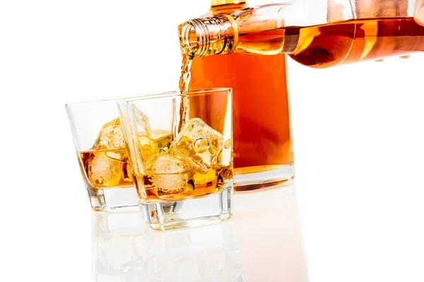 Barman vertiendo whisky en los vasos delante de la botella sobre fondo blanco con reflejo —  Fotos de Stock