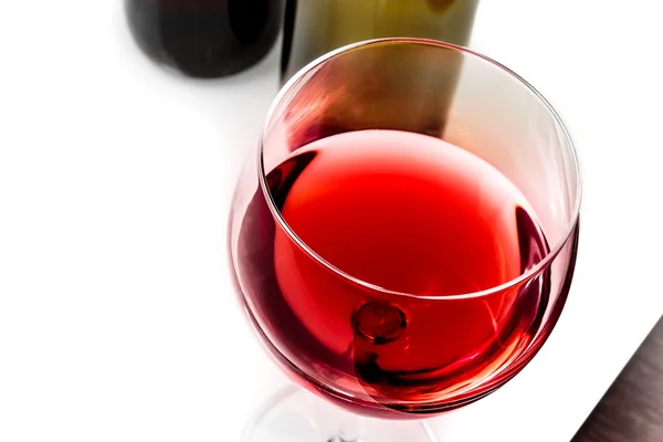 Top of view of red wine glass near wine bottles — Stock Photo, Image