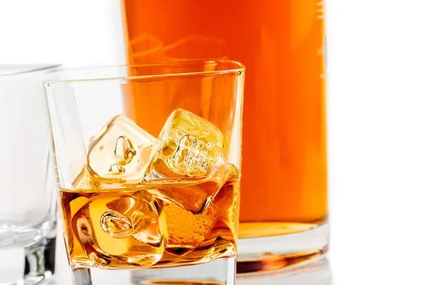 Two glasses of whiskey near bottle on white background with reflection — Stock Photo, Image