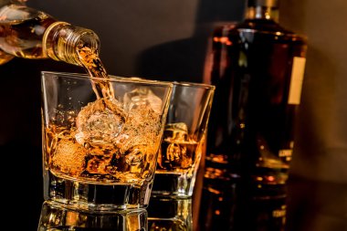 Barmen önünde viski bardak ve şişe viski yağıyor
