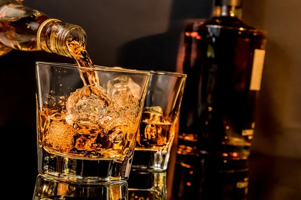 Bartendern hälla whiskey whiskey glas och flaskor — Stockfoto