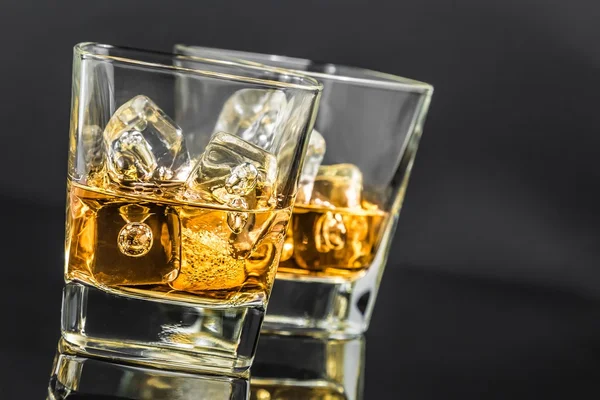 Two glasses of whiskey with ice cubes on dark background — Stock Photo, Image