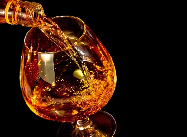 Barman verter snifter de brandy en elegante vidrio de coñac típico sobre fondo negro — Foto de Stock