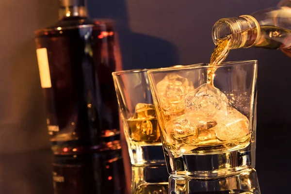 Barman derramando uísque na frente de vidro de uísque e garrafa — Fotografia de Stock