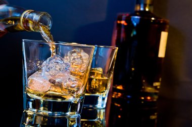 Barmen dökme viski ile hafif renk tonu mavi ve yansıma masada buz küpleri ile iki gözlük
