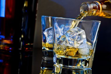 Barmen dökme viski ile hafif renk tonu mavi ve yansıma masada buz küpleri ile iki gözlük