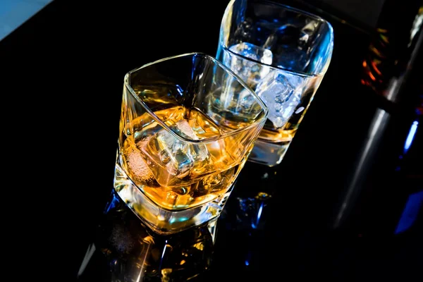 Top of view of glass of whiskey near bottle on black table with reflection — Stock Photo, Image