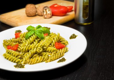 tabak makarna pesto Cenevizli sos ve sebzeler, domates ve fesleğen siyah ahşap masa üzerinde