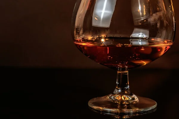 Snifter of brandy in elegant typical cognac glass on dark background — Stock Photo, Image