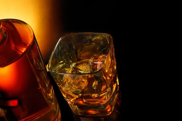 Top of view of glass of whiskey near bottle on black table with reflection — Stock Photo, Image