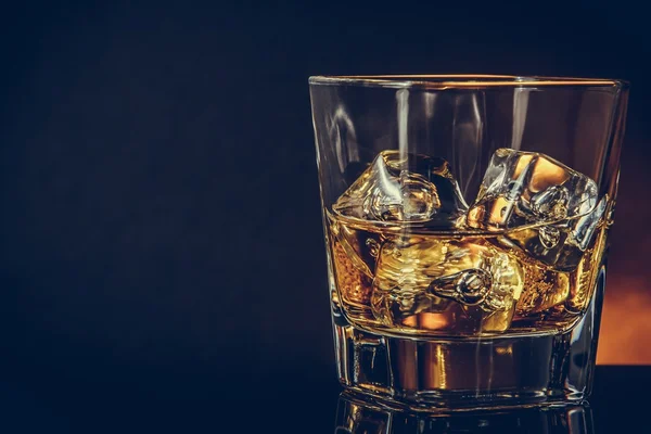 Bicchiere di whisky su fondo nero con riflesso, atmosfera calda — Foto Stock