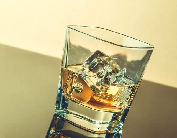 Vaso de whisky en la mesa con reflexión, ambiente cálido — Foto de Stock