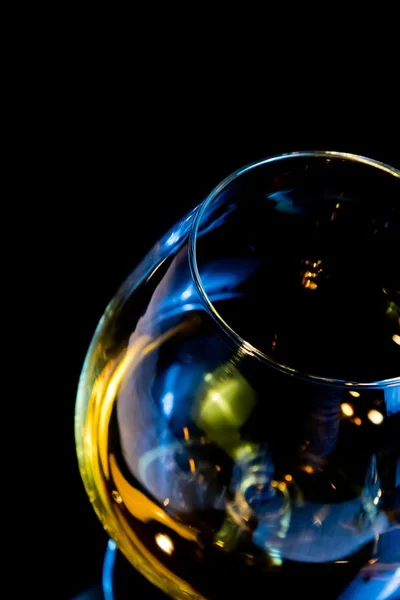 Parte superior de la vista de snifter de brandy en elegante vidrio de coñac típico sobre fondo negro con reflejo azul — Foto de Stock