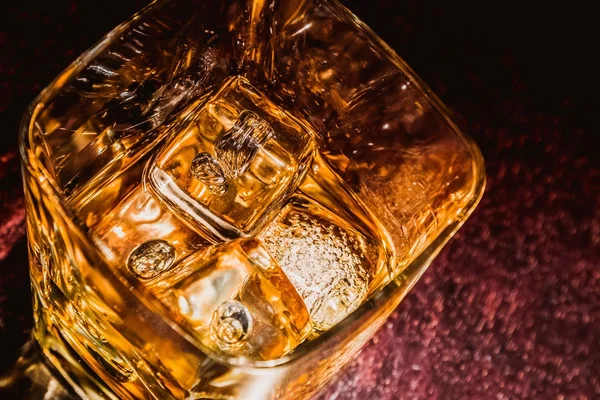 Top of view of glass of whiskey on wood table with focus on ices, warm atmosphere — Stock Photo, Image