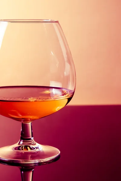 Snifter de brandy en elegante vidrio típico de coñac sobre fondo discoteca de color púrpura claro — Foto de Stock