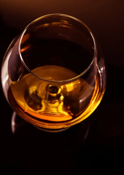 Top of view of snifter of brandy in elegant typical cognac glass on dark background with golden reflection — Stock Photo, Image