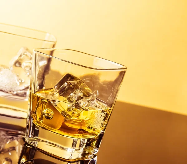 Due bicchieri di whisky sul tavolo con riflesso, atmosfera calda — Foto Stock