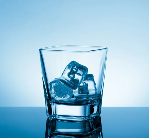 Bicchiere vuoto di whisky su tavolo nero con riflesso e ghiaccio su fondo azzurro — Foto Stock