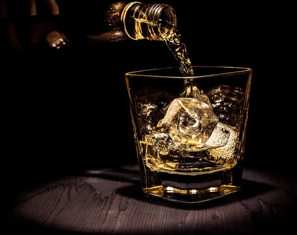 Barman verter whisky en el vaso en la mesa de madera, ambiente cálido, estilo antiguo, tiempo de relax con whisky — Foto de Stock