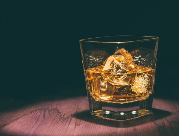 Vista panoramica del bicchiere di whisky con cubetti di ghiaccio sul tavolo in legno, atmosfera calda, momento di relax con whisky — Foto Stock