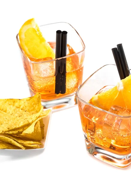 Вид зверху на дві склянки аперитивного коктейлю Скритца з апельсиновими скибочками та кубиками льоду біля чіпсів — стокове фото