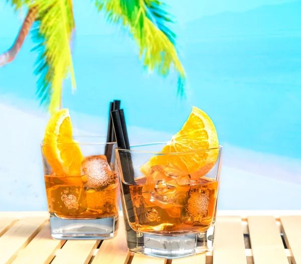 Dwie szklanki aperol aperitifem spritz koktajl z plastrami pomarańczy i kostki lodu na plaży rozmycie tła — Zdjęcie stockowe