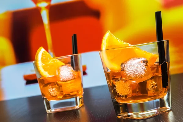 Two glasses of spritz aperitif aperol cocktail with orange slices and ice cubes on bar table, disco atmosphere background — Stock Photo, Image